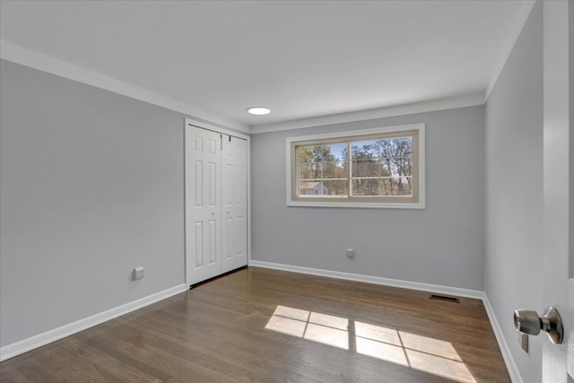 unfurnished bedroom with baseboards, wood finished floors, and a closet