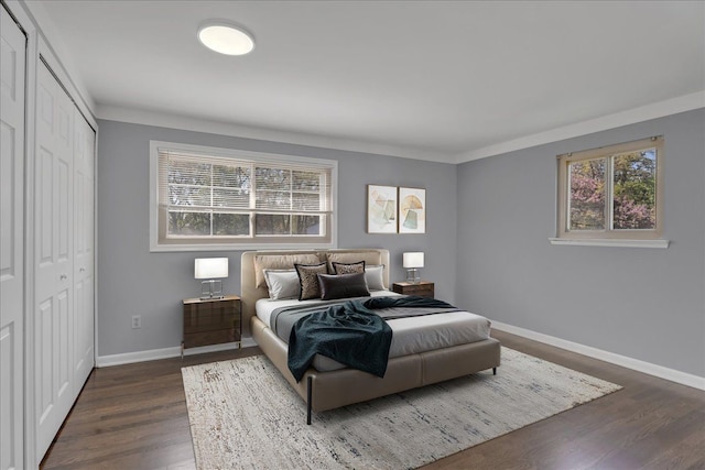 bedroom featuring baseboards, dark wood-style flooring, a closet, and crown molding