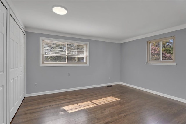 unfurnished bedroom with baseboards, a closet, dark wood-style floors, and crown molding