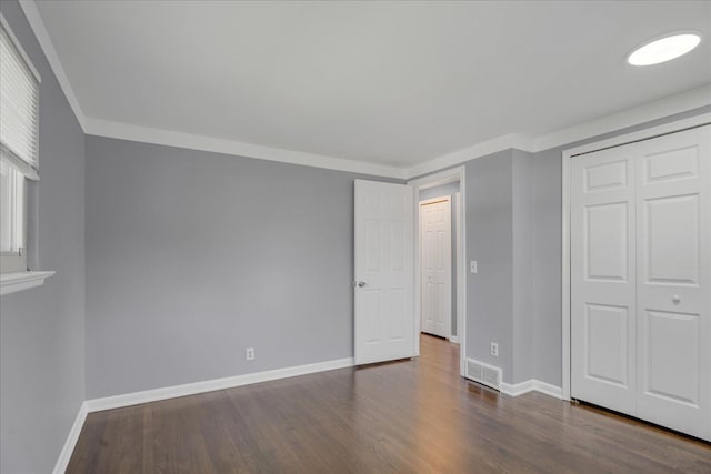 unfurnished bedroom with baseboards, dark wood-style floors, a closet, and ornamental molding