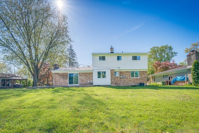 rear view of property with a lawn, brick siding, and a chimney