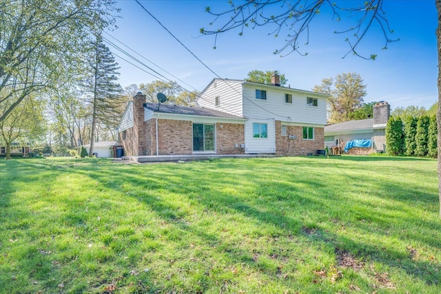 rear view of house with brick siding, a lawn, and a chimney