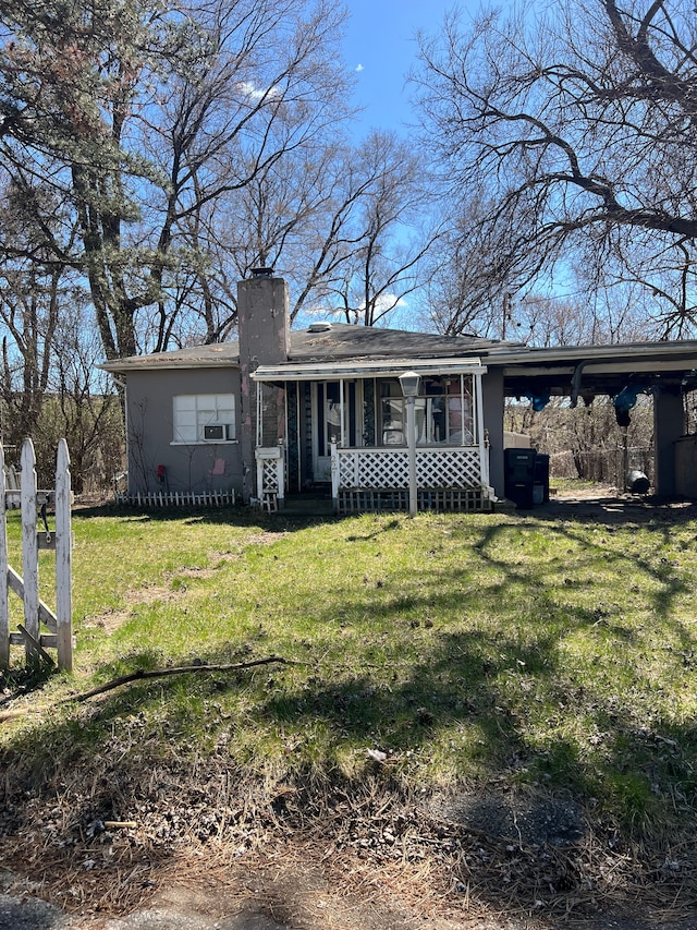 ranch-style home featuring a chimney, a front yard, a carport, and a porch
