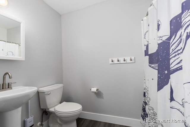 2445 Honey Creek Ave NE, Ada, MI 49301 - bathroom featuring wood finished floors, toilet, a sink, baseboards, and a shower with shower curtain