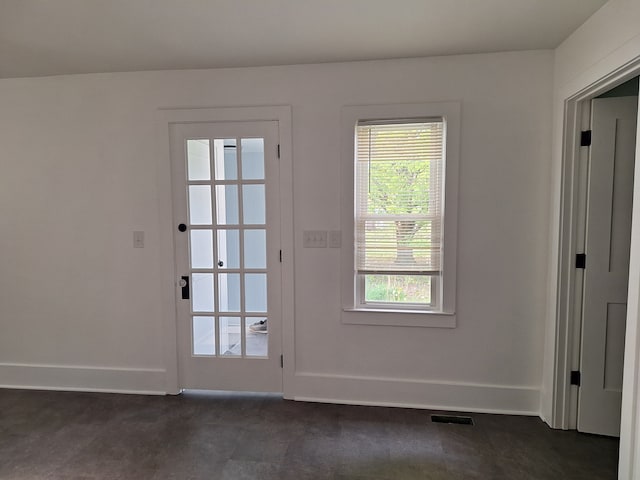 doorway to outside featuring baseboards and dark carpet