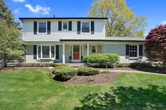view of front facade with brick siding, a front yard, and a porch