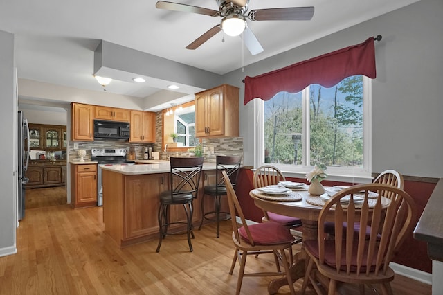 kitchen featuring stainless steel appliances, a peninsula, backsplash, light wood-style floors, and light countertops