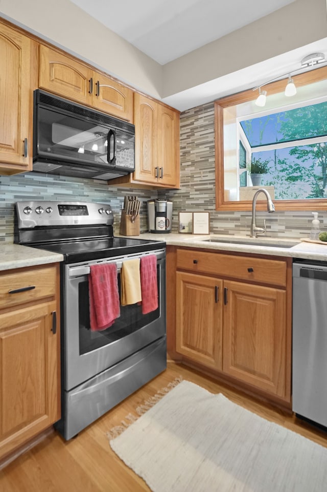 kitchen featuring appliances with stainless steel finishes, a sink, light countertops, and tasteful backsplash