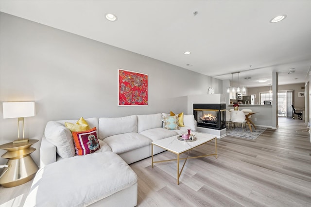 living room with light wood-style floors, a multi sided fireplace, recessed lighting, and baseboards