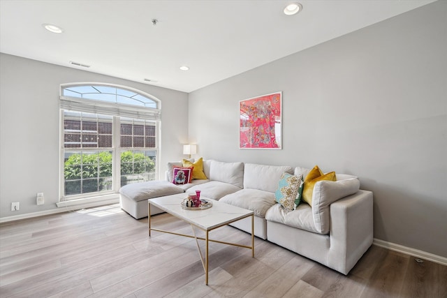 living room with wood finished floors, baseboards, and recessed lighting