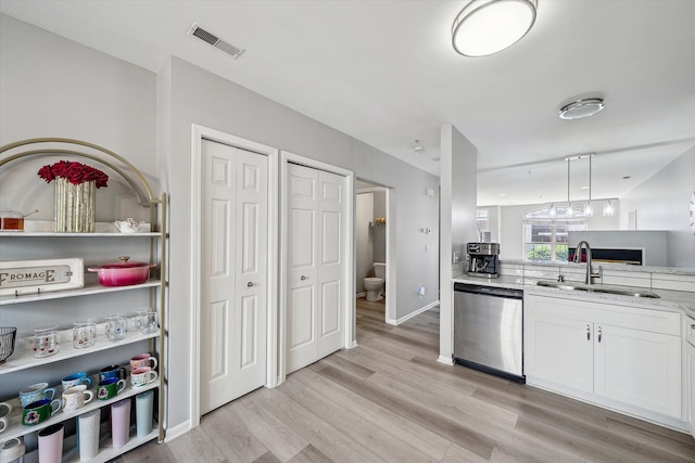 kitchen featuring dishwasher, a sink, light wood finished floors, and white cabinetry