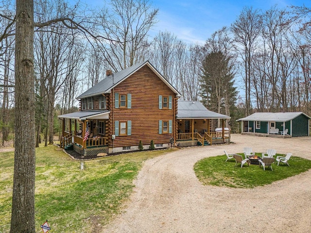 10780 S 29th Rd, Cadillac, MI 49601 - back of property featuring a porch, driveway, an outdoor fire pit, and metal roof