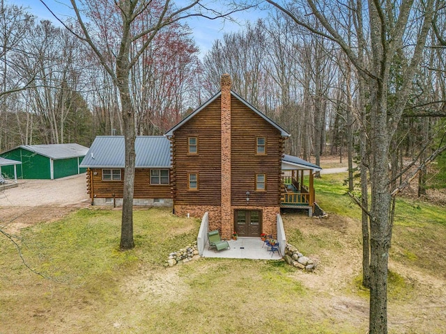 10780 S 29th Rd, Cadillac, MI 49601 - view of home's exterior with log exterior, a chimney, a lawn, metal roof, and a patio