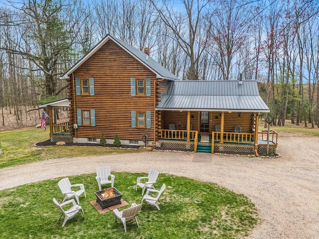 10780 S 29th Rd, Cadillac, MI 49601 - rear view of property with an outdoor fire pit, log siding, a porch, and a lawn