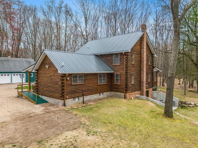 10780 S 29th Rd, Cadillac, MI 49601 - view of home's exterior with log siding, a yard, metal roof, a detached garage, and dirt driveway
