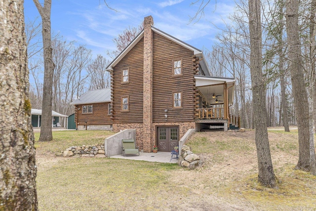 10780 S 29th Rd, Cadillac, MI 49601 - back of house featuring log exterior, a ceiling fan, a yard, and a chimney