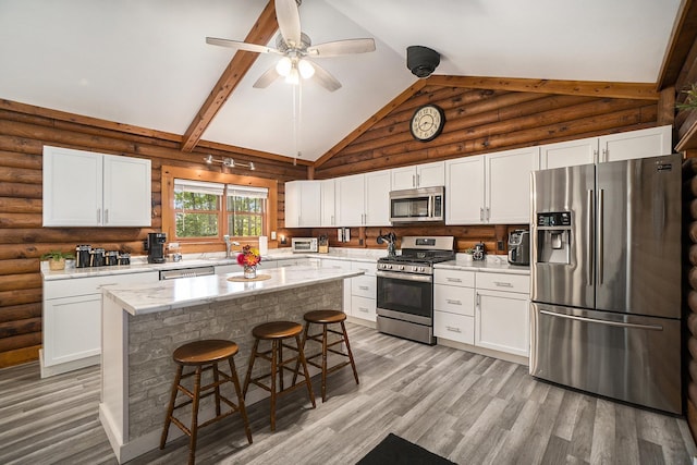 10780 S 29th Rd, Cadillac, MI 49601 - kitchen with stainless steel appliances, a kitchen bar, light wood-style floors, white cabinetry, and high vaulted ceiling