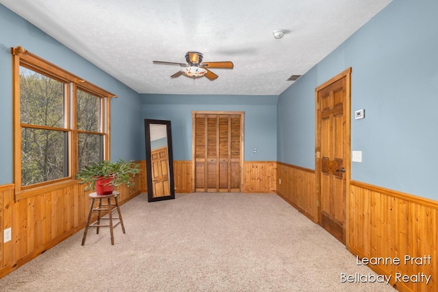 3389 Shultz Rd, Hastings, MI 49058 - carpeted empty room with wood walls, a wainscoted wall, a ceiling fan, a textured ceiling, and a smoke detector