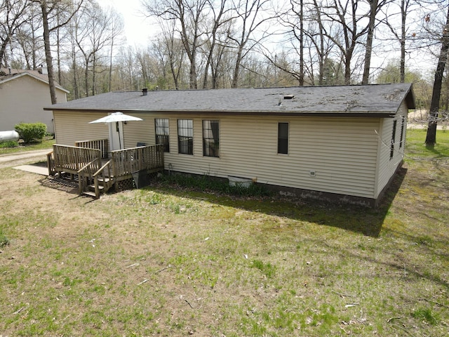 back of property with a deck and a lawn