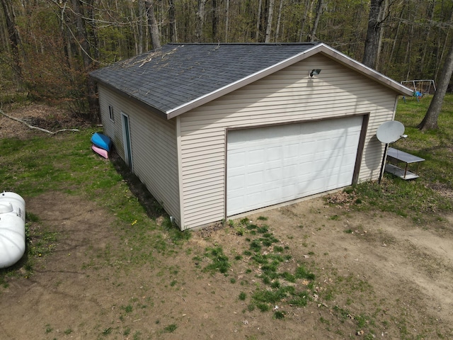 detached garage featuring a view of trees