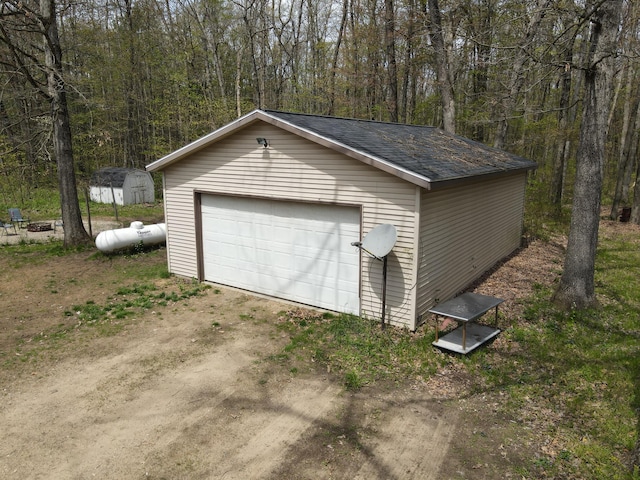 detached garage featuring a view of trees