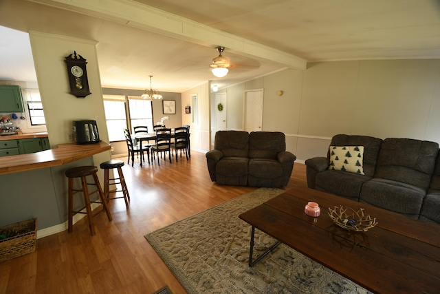 living area featuring wood finished floors, beam ceiling, a chandelier, a ceiling fan, and baseboards