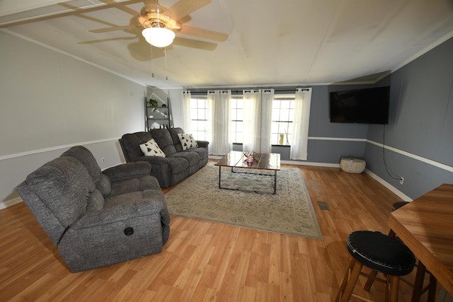 living room with wood finished floors, a ceiling fan, crown molding, and baseboards