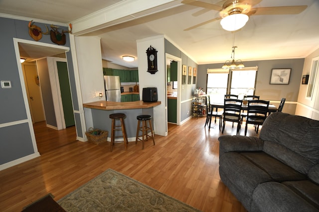 living room with crown molding, ceiling fan, wood finished floors, baseboards, and vaulted ceiling