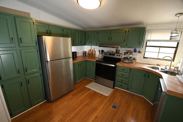 kitchen with stainless steel appliances, butcher block countertops, a sink, ventilation hood, and dark wood-type flooring