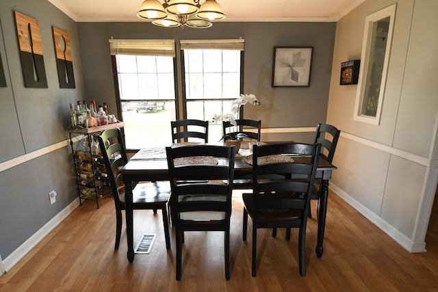 dining area with a chandelier, wood finished floors, ornamental molding, and baseboards