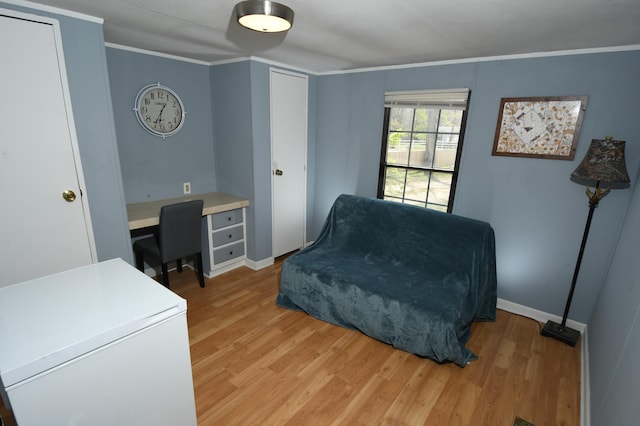 living area with light wood-style floors, crown molding, and baseboards