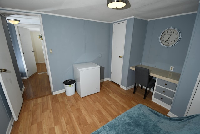 bedroom with white fridge, light wood-type flooring, baseboards, and ornamental molding