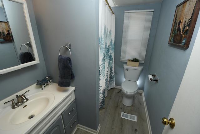 bathroom featuring toilet, vanity, wood finished floors, and baseboards