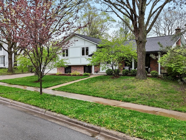 view of front of property with brick siding, a front yard, and concrete driveway