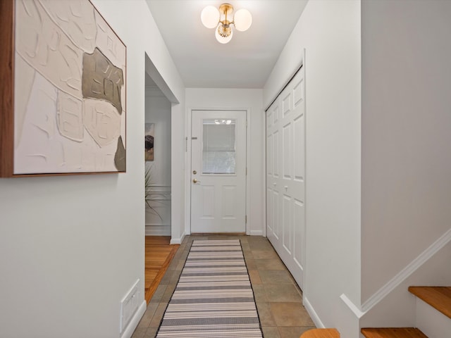 doorway with baseboards and light tile patterned floors