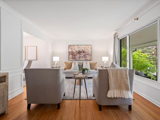 living room featuring ornamental molding, a decorative wall, and wood finished floors