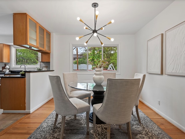 dining space featuring a chandelier, light wood-style flooring, and baseboards
