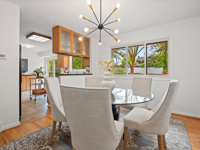 dining area with a chandelier, light wood-type flooring, and baseboards