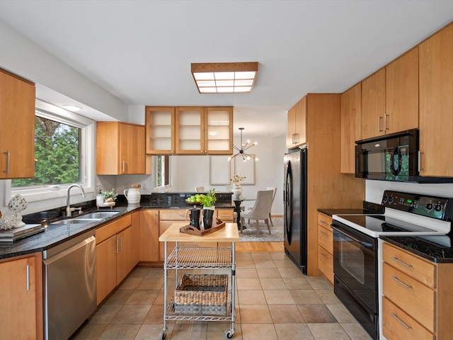 kitchen with black appliances, a sink, a chandelier, dark stone counters, and glass insert cabinets