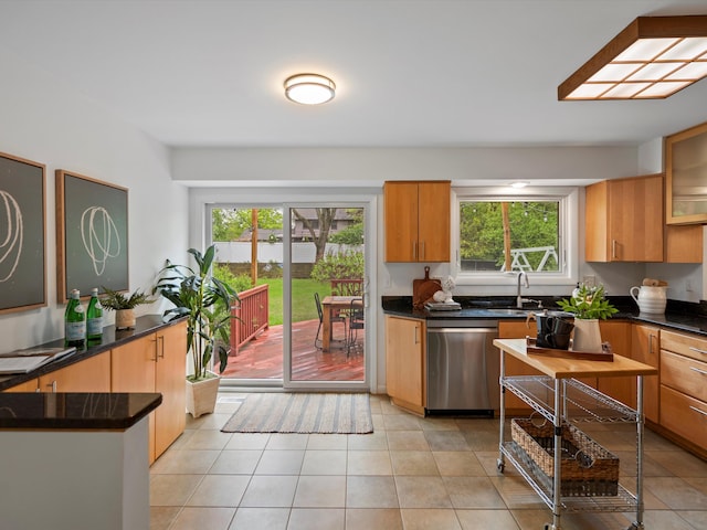 kitchen with stainless steel dishwasher, dark countertops, and light tile patterned floors