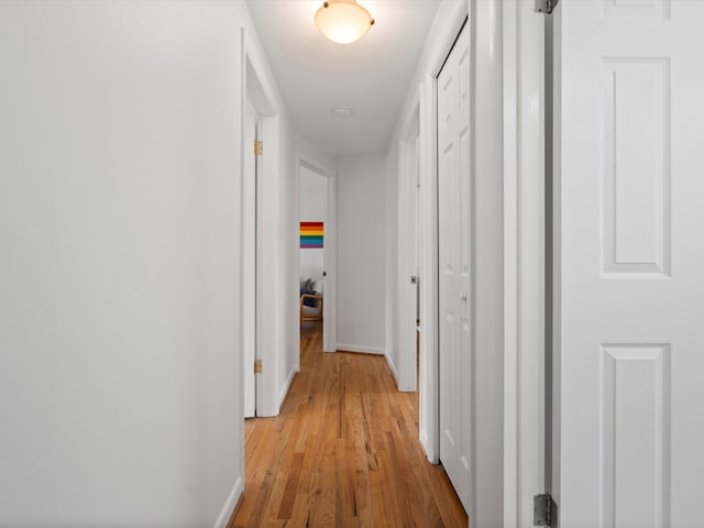 hall featuring light wood-style flooring and baseboards
