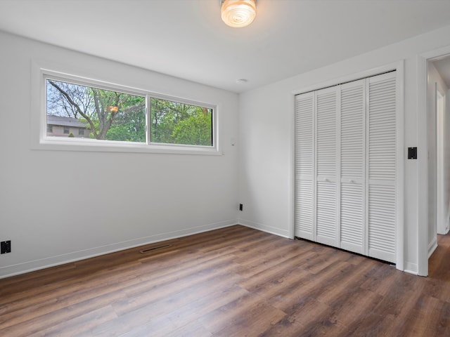 unfurnished bedroom featuring a closet, wood finished floors, and baseboards