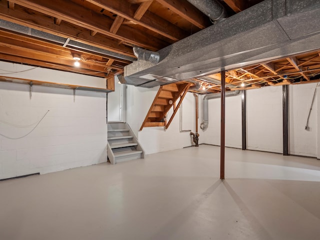 unfinished basement with stairs and concrete block wall