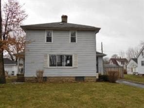 rear view of house featuring a yard and a chimney