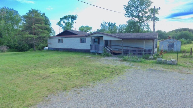 17931 30th Ave, Barryton, MI 49305 - view of front facade with a front lawn, a storage unit, an outdoor structure, a deck, and gravel driveway