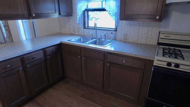 17931 30th Ave, Barryton, MI 49305 - kitchen with white range with gas stovetop, a sink, light countertops, wallpapered walls, and wood finished floors