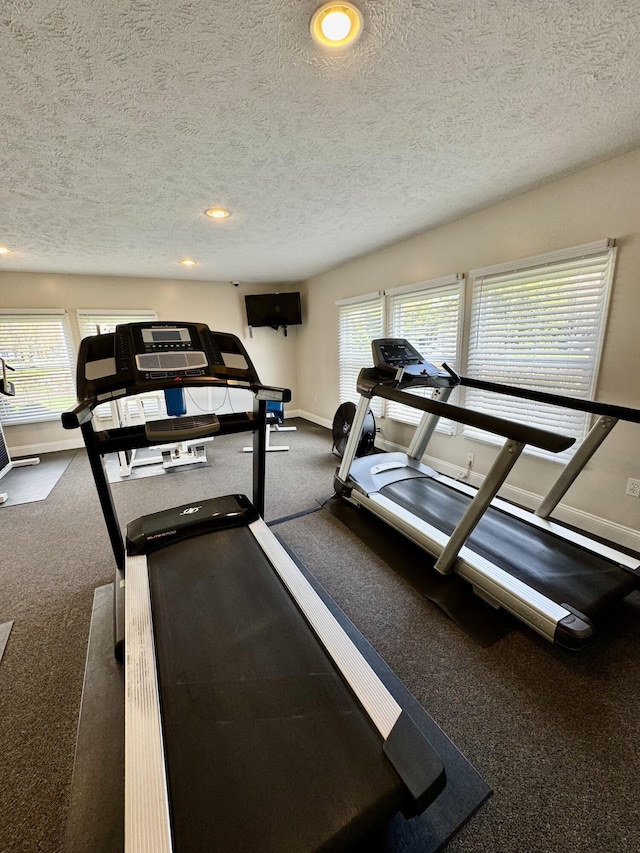 exercise room featuring baseboards, plenty of natural light, carpet floors, a textured ceiling, and recessed lighting