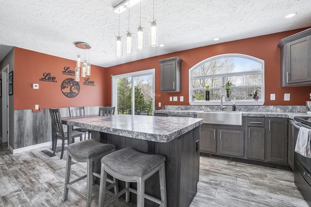 554 Ottawa Trl, Buckley, MI 49620 - kitchen with a textured ceiling, a sink, a center island, a kitchen breakfast bar, and electric stove