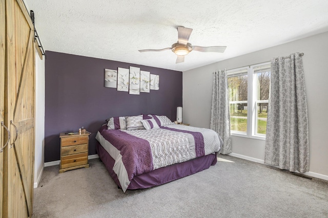 554 Ottawa Trl, Buckley, MI 49620 - bedroom with a barn door, carpet, baseboards, a textured ceiling, and a ceiling fan