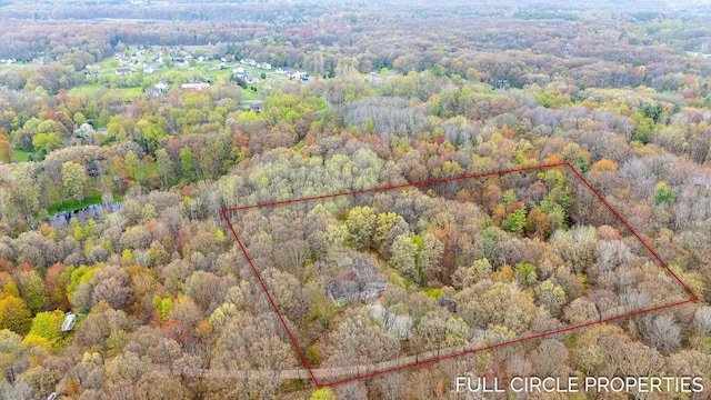 aerial view of property and surrounding area featuring a heavily wooded area and property boundaries highlighted